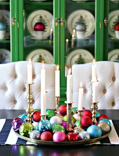 a plate with candles and ornaments on it in front of a green china hutch