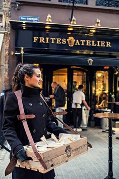 a woman is standing on the street with some food in her hand and looking at something