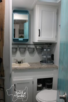 a bathroom with a toilet, sink and mirror