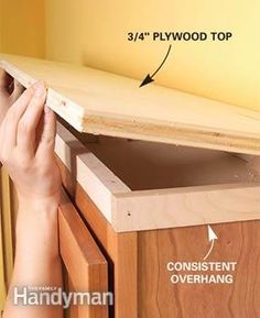 a person is working on the top of a cabinet with plywood and wood trimmings