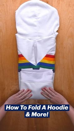 someone is holding up a white hoodie with rainbow stripes on it and the words how to fold a hoodie & more