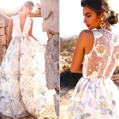 a woman in a white dress standing next to a stone wall and looking back at the camera