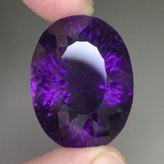 a person holding a large purple diamond in their left hand and the other hand is holding it