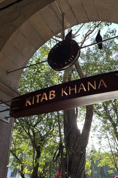 a sign hanging from the side of a building that says kitab khana