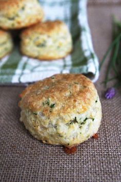 some biscuits are sitting on a table next to purple flowers and a green checkered towel