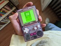 a person is holding an old gameboy in their left hand, with the screen turned green