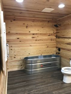 a bathroom with wood paneling and a metal tub in the corner next to a toilet