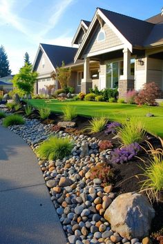 a house with lots of rocks and plants in front of the house on a sunny day