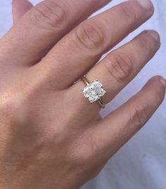 a woman's hand with a diamond ring on top of her finger, and the other hand holding an engagement ring