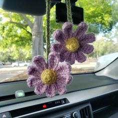 two crocheted flowers hanging from a car dashboard