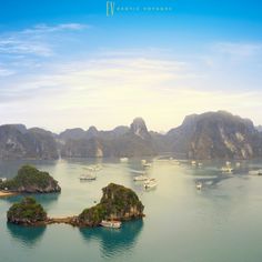 an aerial view of many boats in the water near some mountains and rocks, with blue sky