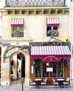 the outside of a building with tables and chairs on the sidewalk in front of it