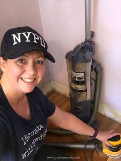 a woman is smiling next to a vacuum