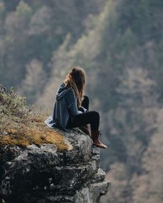 a woman sitting on top of a cliff