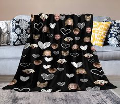 a black blanket with hearts and cats on it, sitting in front of a couch