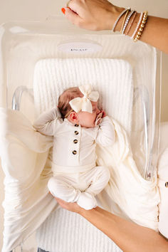 a woman holding a baby in a clear box with her hand on the back of it