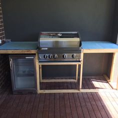 an outdoor bbq with grill and sink on wooden flooring next to brick wall