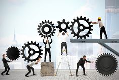 several people are standing in front of giant gears and holding hands up to each other