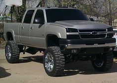 a silver truck parked on top of a parking lot next to a white pickup truck