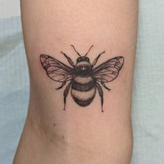 a small bee tattoo on the right side of the leg, it is black and white