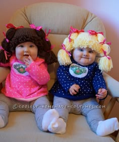 two baby dolls sitting next to each other on a chair