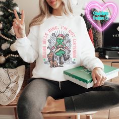 a woman sitting on a chair holding a green box and giving the peace sign with her hand