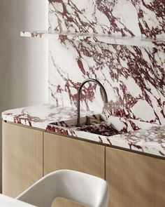 a kitchen with marble counter tops and white chairs in front of the sink that has a faucet on it