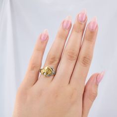 a woman's hand wearing a gold ring with a diamond in the middle and an elephant head on it