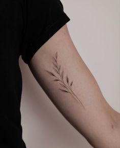 a woman's arm with a small branch tattoo on the left side of her arm