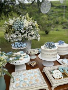 a table topped with cakes and desserts on top of a wooden table covered in flowers