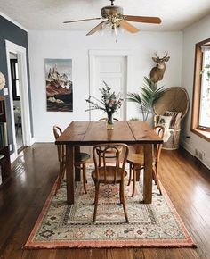 a dining room table with chairs and a rug on the floor in front of it