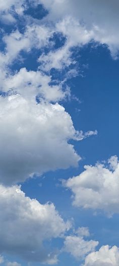 the airplane is flying high in the blue sky with white clouds above it and below