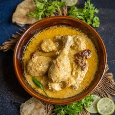 a bowl filled with chicken curry and garnished with cilantro, parsley