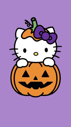 hello kitty sitting on top of a jack - o'- lantern with a purple background