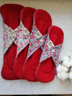 four pairs of red slippers sitting on top of a counter next to cotton balls