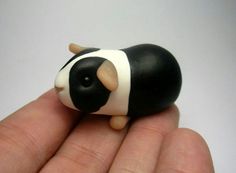 a hand holding a small black and white toy cow