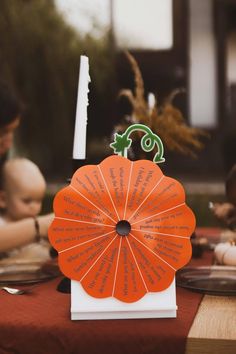 an orange fan sitting on top of a table next to a plate with writing on it