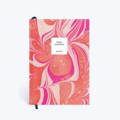 an orange and pink notebook with a black pen