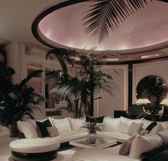 a living room filled with lots of white furniture and large palm tree in the corner