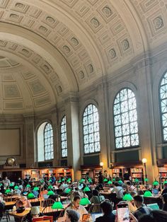 a large room filled with lots of people sitting at tables in front of bookshelves