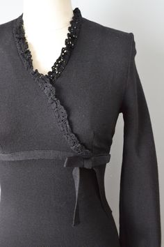 "Early 1960s black wool knit dress from Jonathan Logan. Surplice bodice and long sleeves, both trimmed in wool crocheted lace, with button closures at the wrists. Empire waist trimmed with a knit ribbon and side bow. Straight skirt. Back painted metal zipper. Size- Extra Small - Small, with stretch in the knit Bust - 30-34\" Empire seam 32-34\" Waist - 25-28\" Hips - 30-34\" Length - 39\" Label: Jonathan Logan Condition: Excellent vintage condition. One little rough edge on the back knit ribbon Elegant Fitted Dress With Crochet Trim, Elegant Long Sleeve Dress With Crochet Trim, Fitted Long Sleeve Dress With Crochet Trim, Classic A-line Vintage Dress With Button Closure, Black A-line Dress With Button Closure, 1960s Black Dress, House Of Harlow 1960 Sweater Dress, Black V-neck Dress With Button Closure, Jonathan Logan