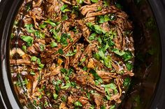 a slow cooker filled with shredded meat and garnished with cilantro