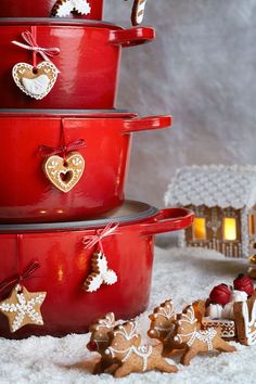 three red pots are stacked on top of each other and decorated with gingerbread cookies