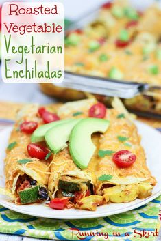 an enchilada is on a plate with tomatoes and avocado