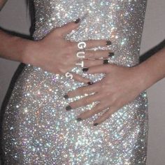 a woman in a silver dress with her hands on her stomach and the word love spelled out