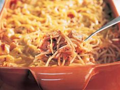 a casserole dish with noodles and meat in it on a red plate, ready to be eaten