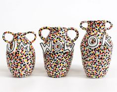 three colorful vases with the word wow painted on them are lined up against a white background