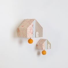 two pieces of wood with oranges hanging from them on a white wall next to each other