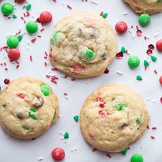 three cookies with candy and sprinkles on a white surface