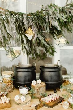 two black caulders sitting on top of a wooden table next to christmas decorations